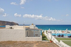 A coastal property with a swimming pool, lounge chairs, and a view of the sea. - Apartment 'Pool Suite 1' with Shared Pool and Balcony (Αρκάσα)