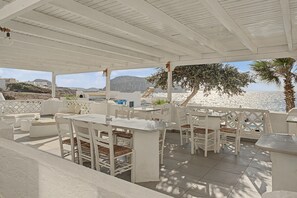 An outdoor seating area with white furniture, a view of the sea, and a mountainous landscape in the background. - Apartment 'Pool Suite 1' with Shared Pool and Balcony (Αρκάσα)