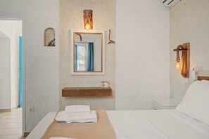 Ein Schlafzimmer mit einem Bett, einer Holzregal, einem Spiegel und einer Wandleuchte.