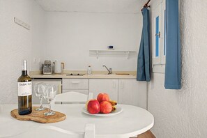 Eine kleine Küchenzeile mit weißer Arbeitsplatte, einer Kaffeemaschine, einem Wasserkocher und einem Spülmittelspender.