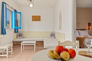 Ein Zimmer mit einem weißen Sofa, einem kleinen Tisch, einer Wandleuchte und einem Bett mit Kopfteil.