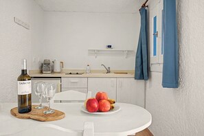 A small kitchenette with a coffee maker, a bottle of wine, and a plate of fruit. - Apartment 'Bangalow 1' with Sea View, Wi-Fi and Air Conditioning (Αρκάσα)