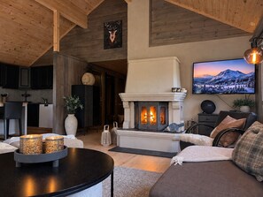 Ein gemütliches Wohnzimmer mit Kamin, Fernseher und Essbereich mit dunklen Holzschränken.