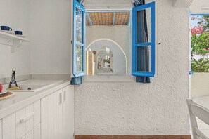 Ein Badezimmer mit weiß geflieste Wand, einem Waschbecken, einem Spiegel und einem Fenster mit blauen Rollläden.
