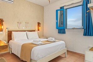 Ein Schlafzimmer mit Bett, Nachttisch, Wandlampe und einem Fenster mit Vorhängen.