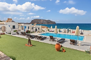 A poolside area with lounge chairs and umbrellas, a clear view of the sea, and a mountainous backdrop. - Apartment 'Pool Suite 5' with Sea View, Wi-Fi and Air Conditioning (Αρκάσα)
