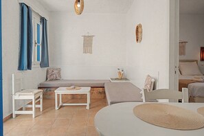 A cozy room with a bed, a bench, a table, and a chair. - Apartment 'Pool Suite 6' with Shared Pool and Balcony (Αρκάσα)