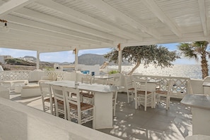 An outdoor seating area with white furniture, a view of the sea, and a mountainous landscape in the background. - Apartment 'Pool Suite 6' with Shared Pool and Balcony (Αρκάσα)