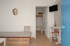 A room with a bed, a desk with a chair, a television, and a door leading to another room. - Apartment 'Pool Suite 8' with Shared Pool and Balcony (Αρκάσα)
