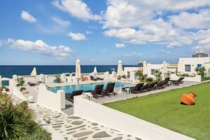 A poolside area with lounge chairs and umbrellas, overlooking the sea. - Studio 'Thalassa Suite 1' with Sea View and Shared Pool (Αρκάσα)