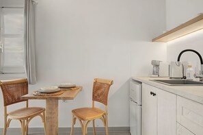 Eine moderne Küche mit Holztisch, zwei Korbstühlen, einem eingebauten Geschirrspüler und einer Kaffeemaschine.