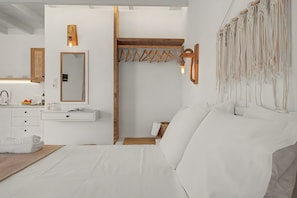 A modern bedroom with a large bed, a wooden headboard, a mirror, and a wall-mounted light fixture. - Studio Apartment 'Thalassa Suite 3' with Sea View and Shared Pool (Αρκάσα)