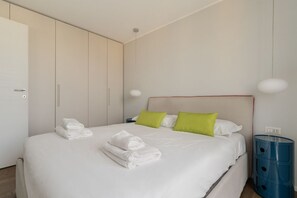 Une chambre d’hôtel avec un lit, des oreillers, une table de chevet et un meuble de rangement bleu.