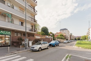 A street view with a row of parked cars, a building with a sign 'ACIA S. MATTEO', and a pedestrian crossing. - A modern and bright 50 sqm one-bedroom apartment with a terrace, suitable for two guests and located near the San Siro Stadium. Situated on the eighth floor of a building (with elevator —though NOT suitable for people with disabilities due to a few ste (Milan)