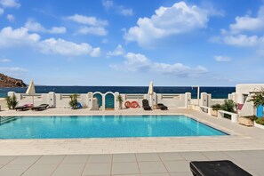 A pool area with lounge chairs, a lifebuoy, and a view of the sea. - Studio Apartment 'Thalassa Suite 4' with Sea View and Shared Pool (Αρκάσα)