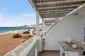 A balcony with a view of the sea, a table with chairs, and a white wall. - Studio Apartment 'Thalassa Suite 4' with Sea View and Shared Pool (Αρκάσα)