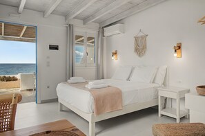 Ein Schlafzimmer mit einem Bett, Nachttischen, Meerblick und einer Wanddeko aus Makramee.