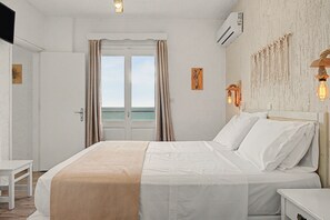 Ein Hotelzimmer mit Bett, Nachttisch, Wandklimaanlage und Blick durch eine Tür.