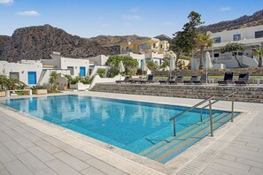 Ein Schwimmbad mit Liegestühlen und einer Steinmauer.