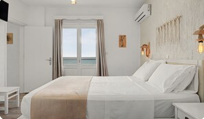 Ein Hotelzimmer mit Bett, Nachttisch, Kleiderschrank, einem Fenster mit Vorhängen und einer Wandklimaanlage.