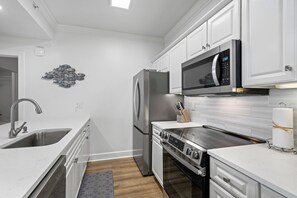 Une cuisine moderne avec des meubles blancs, des appareils en acier inoxydable et un four à micro-ondes encastré.