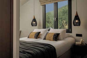 Une chambre à coucher avec un lit, deux tables de chevet et une fenêtre donnant sur un paysage verdoyant.