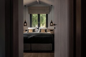 A bedroom with a bed, two hanging lights, a window with a view of trees, and a door. - Villa Verde Zante - Three Bedroom Villa, Sleeps 7 (Kallithea)