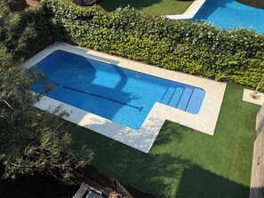 A rectangular swimming pool with a blue interior, surrounded by a white border and a green artificial turf area. - Luxury Penthouse with Terrace, Pool, and Views (Sant Cugat del Vallès)