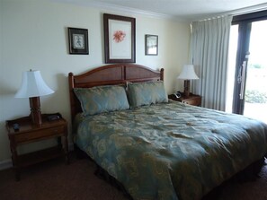 Ein Hotelzimmer mit einem großen Bett, zwei Nachttischen und einem Fenster mit Vorhängen.