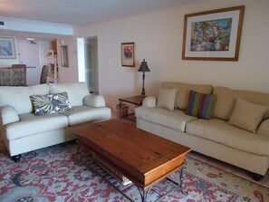 Ein Wohnzimmer mit zwei Sofas, einem Couchtisch und einem gemusterten Teppich.