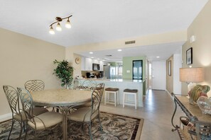 A dining area with a round table, chairs, and a plant. - Edgewater Beach Condo 807 (Destin)