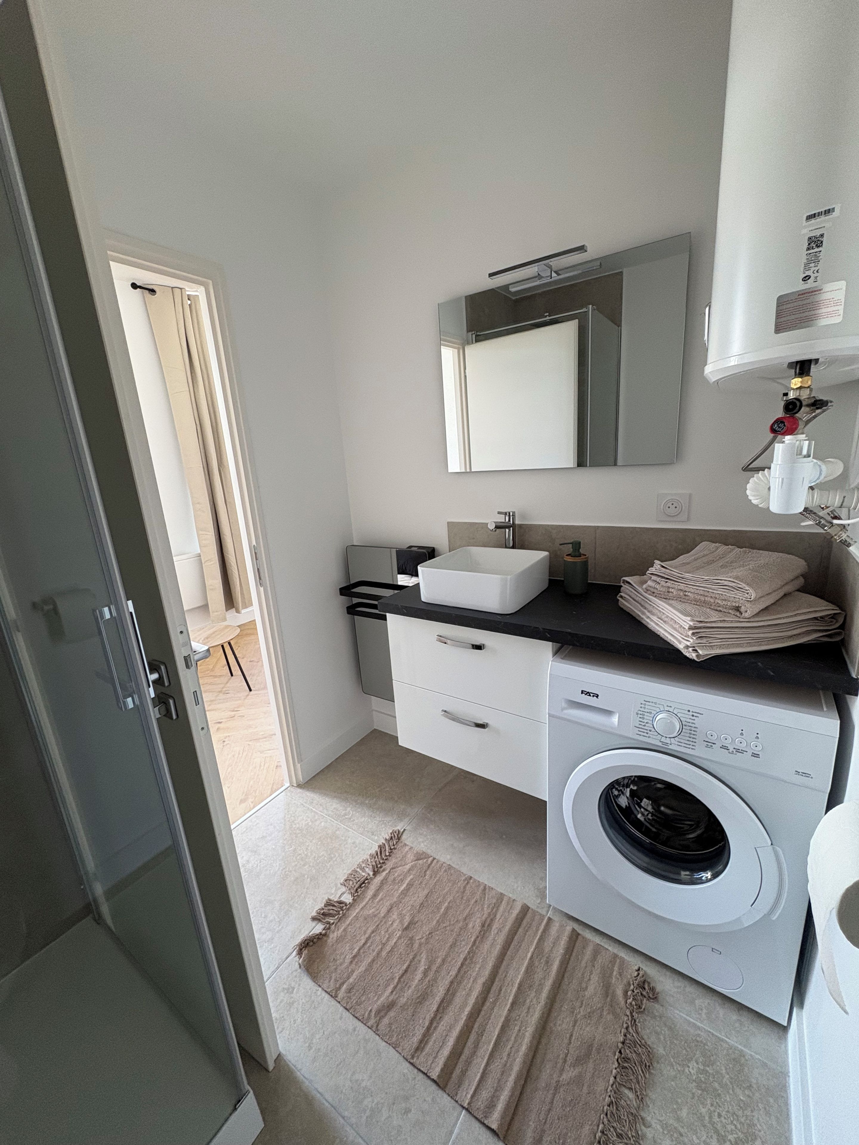 Un baño moderno con lavadora incorporada, un lavabo y un espejo.