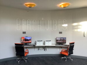 A workspace with two desks, chairs, and a wall-mounted display with the text 'BEACH VIBES'. - Spacious condo Ocean Walk Resort with lazy river (Daytona Beach)