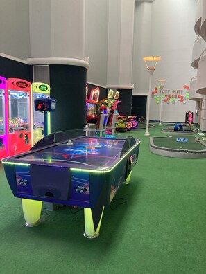 An indoor arcade with various gaming machines, including air hockey tables and claw machines. - Spacious condo Ocean Walk Resort with lazy river (Daytona Beach)