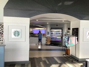 A Starbucks coffee shop with a menu display, a beverage vending machine, and a clothing rack. - Spacious condo Ocean Walk Resort with lazy river (Daytona Beach)