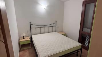 Une chambre avec un lit simple, une table de chevet avec une lampe et une petite commode.
