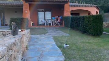 Ein gepflasterter Weg führt zu einem Gebäude mit einem Ziegeldach und einer überdachten Terrasse.