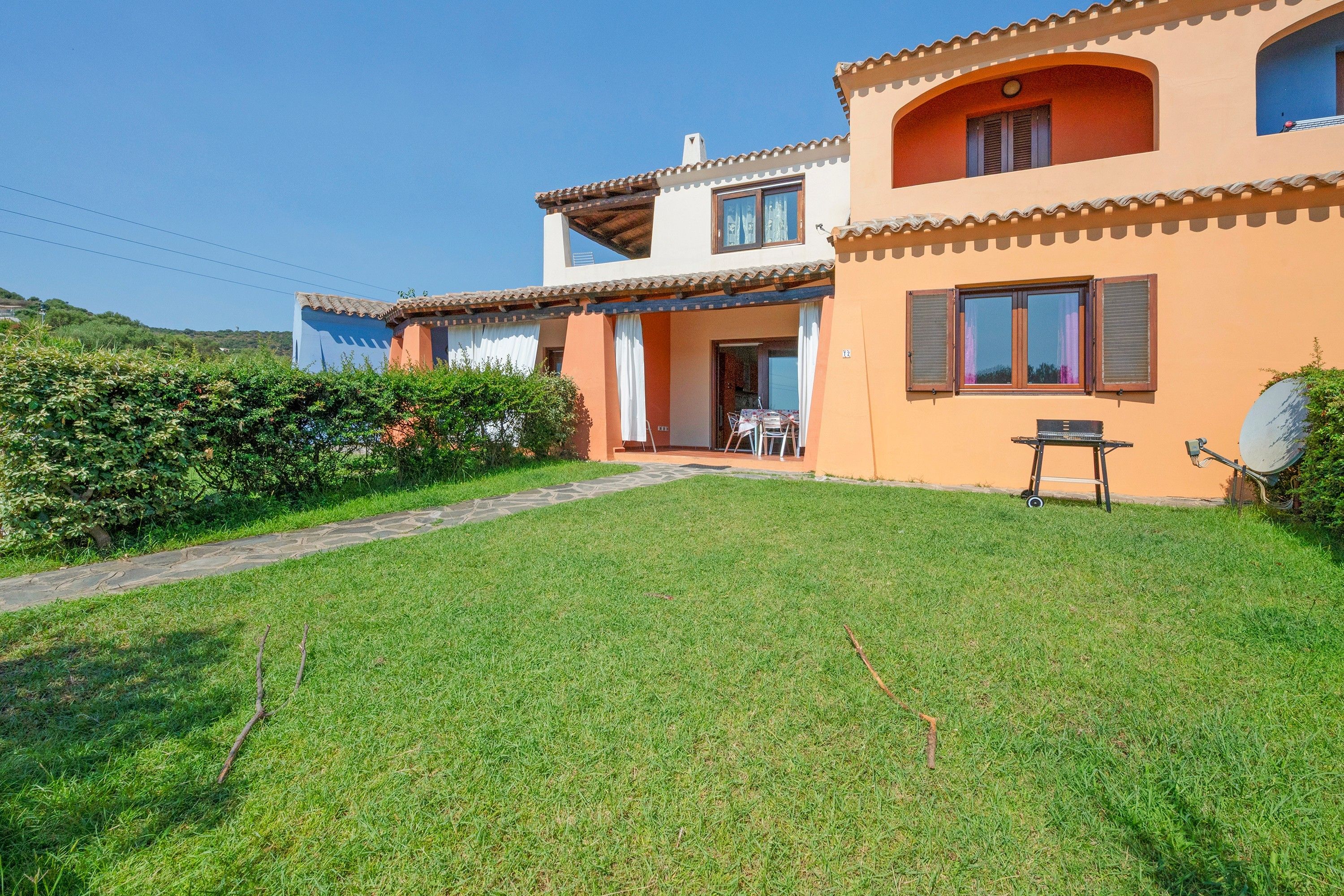 A two-story house with a well-maintained lawn and a patio area.