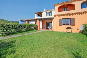 A two-story house with a well-maintained lawn and a patio area.