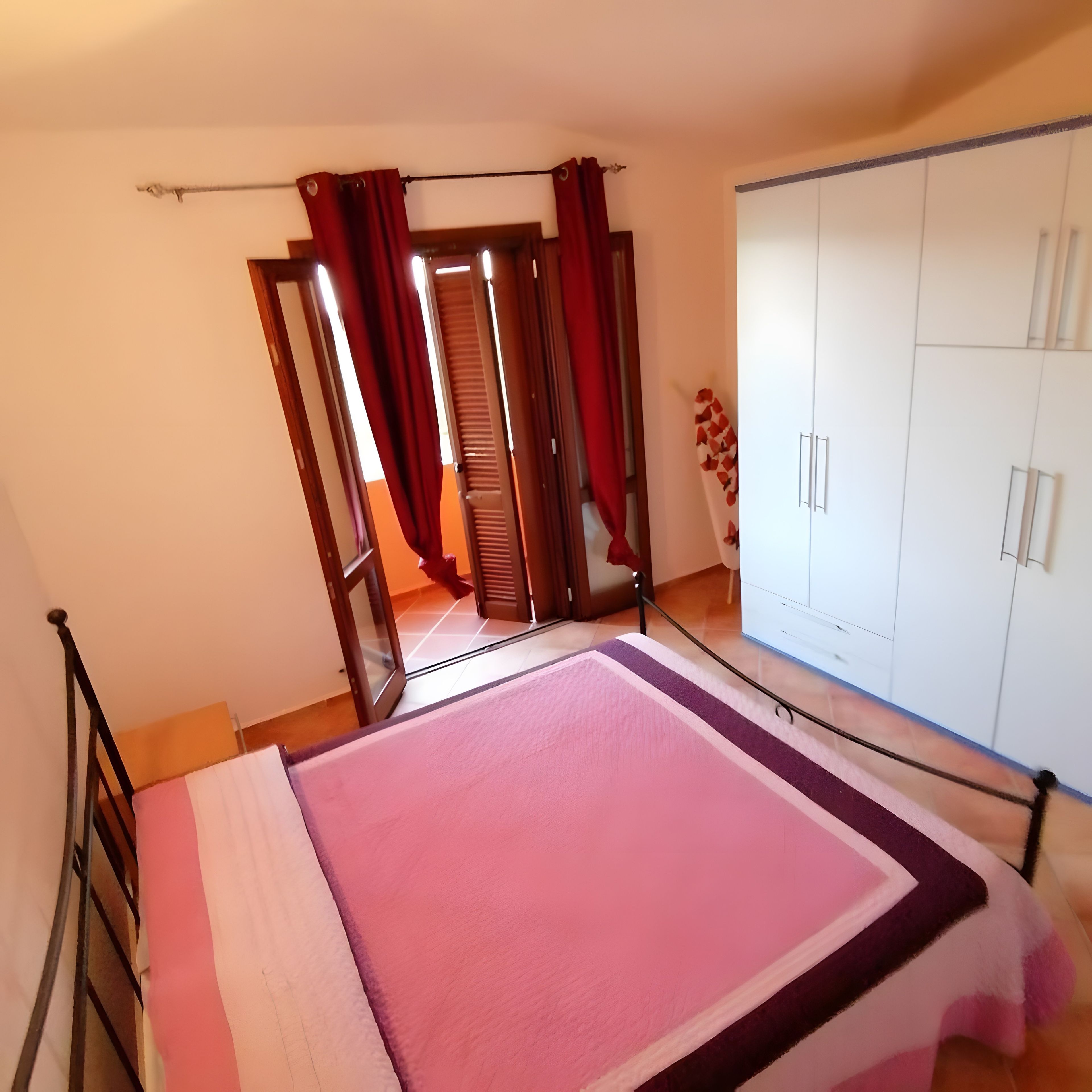 A bedroom with a bed, a wardrobe, and a window with curtains.