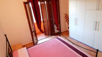A bedroom with a bed, a wardrobe, and a window with curtains.