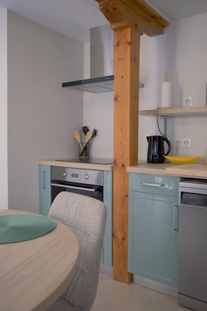 A kitchen with a wooden beam, a stove, a dishwasher, and a coffee maker.