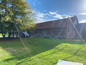 Ein grünes Grundstück mit Schaukeln, einem Baum und einem Haus mit rotem Dach.