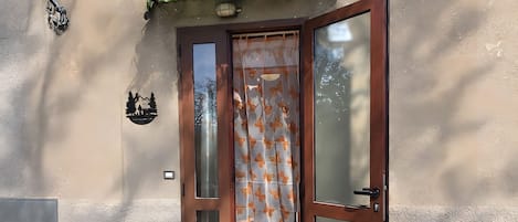 A building entrance with a wooden door, a welcome mat, and a small Santa figurine.