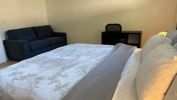 A bedroom with a bed, a sofa, a chair, and a small table.