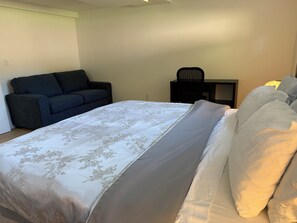 Une chambre à coucher avec un lit, un canapé, une chaise et une petite table.