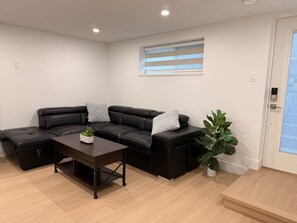 Un salon moderne avec un canapé d’angle, une table basse et une plante en pot.