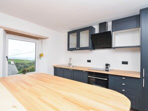 Eine moderne Küche mit einer Holzausziehtheke, dunklen Schränken und einem eingebauten Backofen.