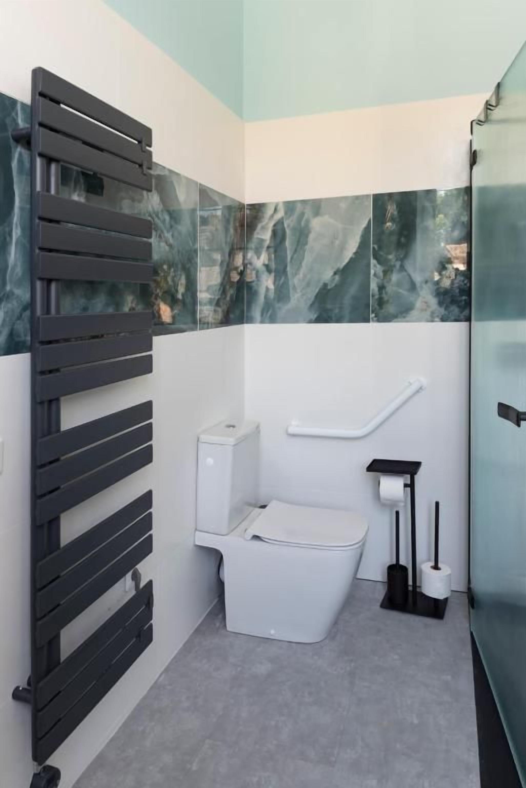 Een badkamer met toilet, douche en een douchecabine met glazen wanden.
