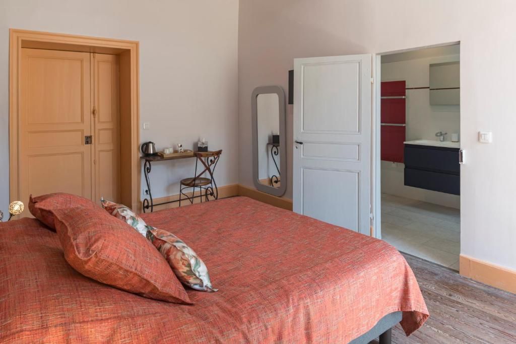 Ein Schlafzimmer mit Bett, Schreibtisch, Stuhl, Spiegel und einem durchgehenden Türspalte sichtbaren Badezimmer.